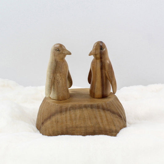 Hand-carved wooden penguin sculpture set on a natural wood base, artisanal sustainable home décor.