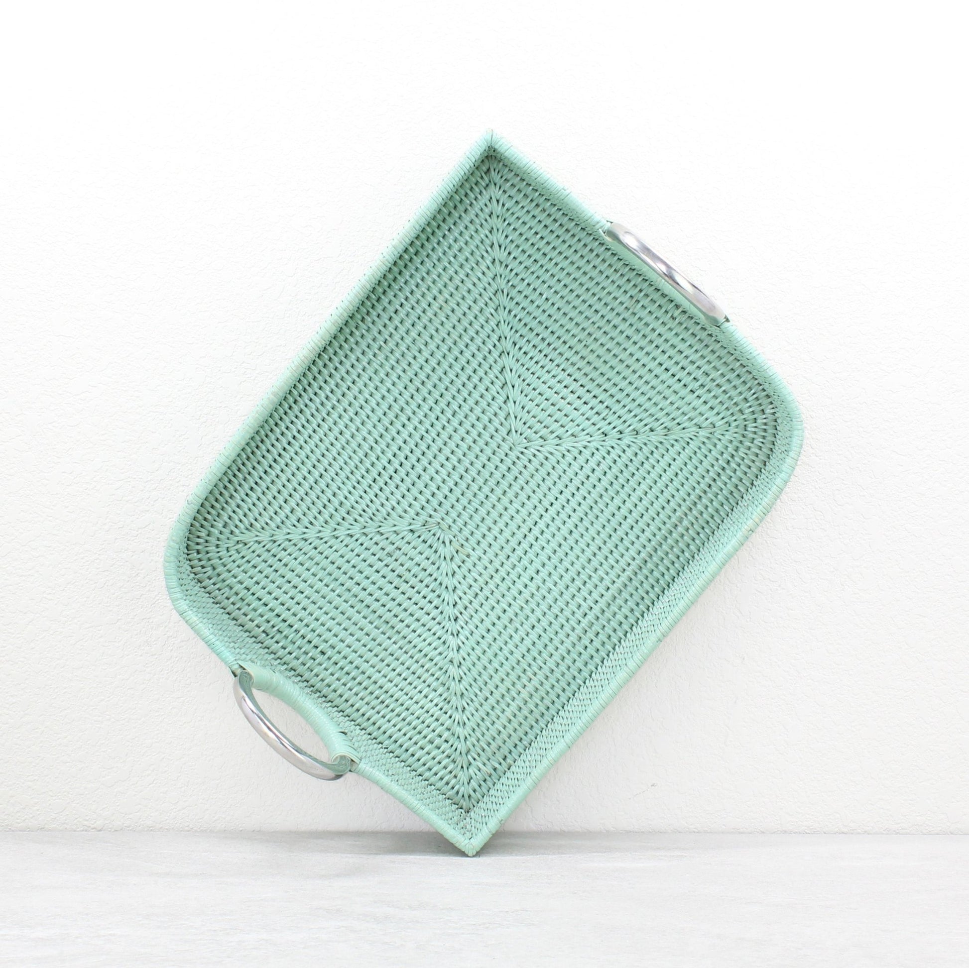 Top view of sage leaf green rattan tray with steel handles showcasing handwoven details.