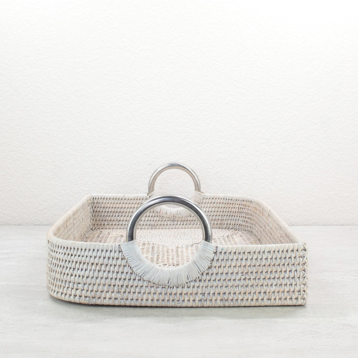 Whitewash leaf shaped rattan tray close-up with steel handles highlighting craftsmanship and weave.