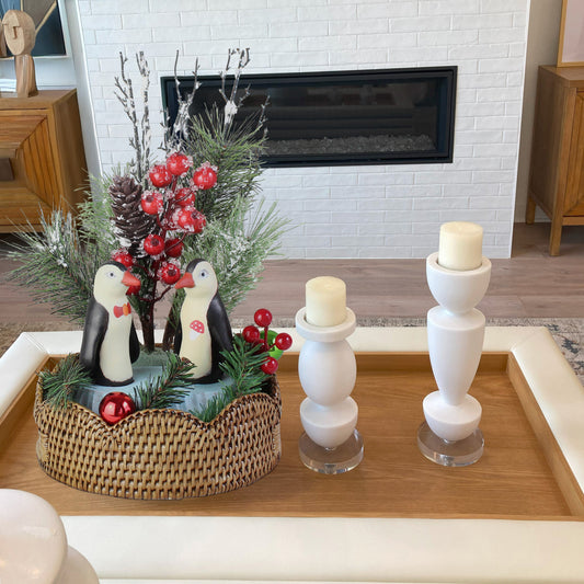 Festive penguin sculpture gift set on scalloped rattan tray styled as Christmas décor centerpiece on a modern coffee table