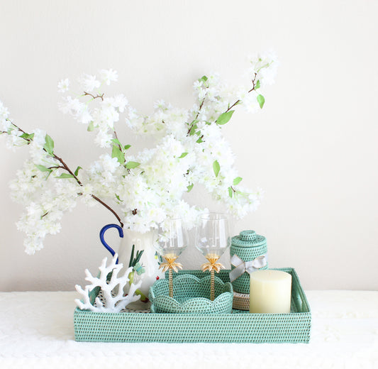 Wedding gift set featuring sage leaf green rattan tray, round scalloped tray, canister with lid, seashell coasters, and floral accents
