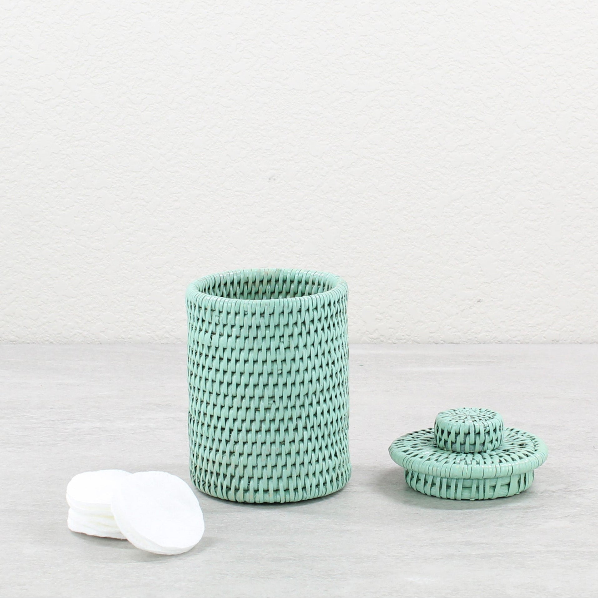 Sustainable sage green rattan round canister with lid, artisan handmade storage jar styled with cotton pads