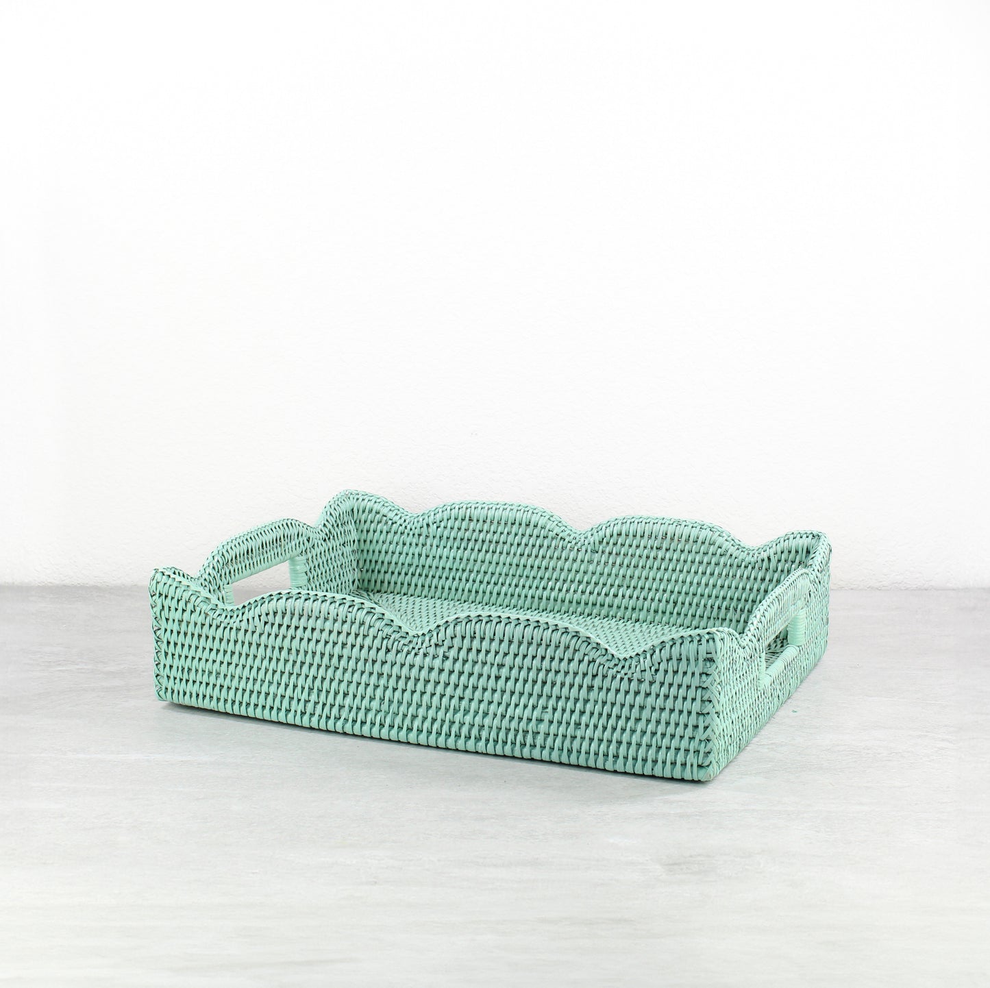 Artisan handwoven sage leaf green scalloped rattan tray, medium size, displayed on a modern neutral background
