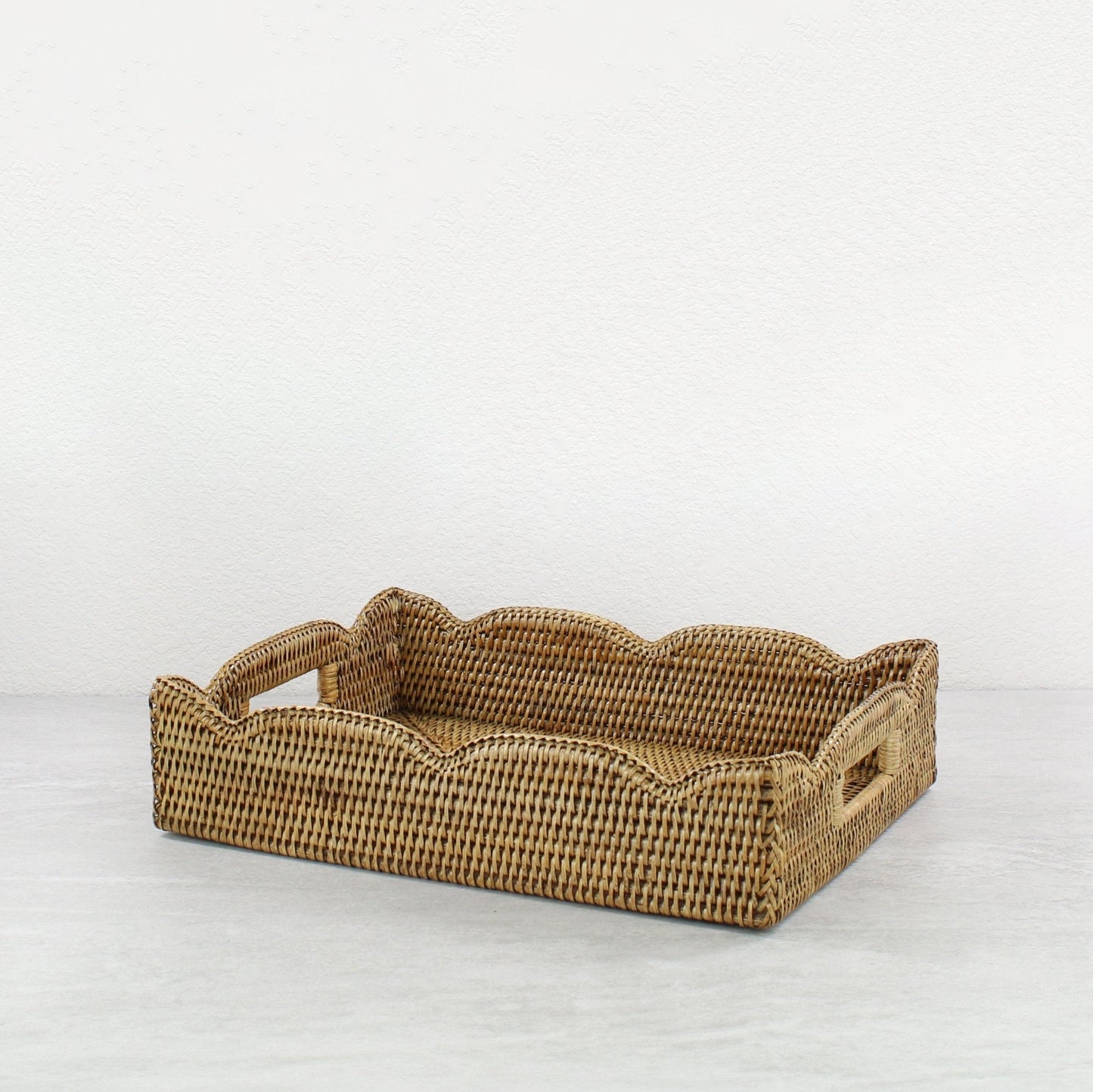 Honey brown medium scalloped rattan tray with handles on a white background, showing handwoven detail.