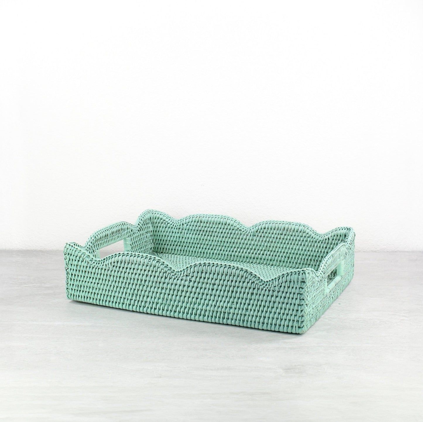 Sage leaf green medium scalloped rattan tray with handles on a white background, showing handwoven detail.