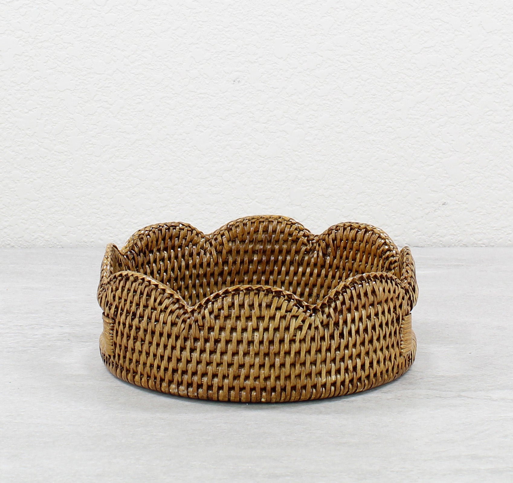 Front view of small scalloped round rattan tray in honey brown, handmade artisan storage basket or serving tray