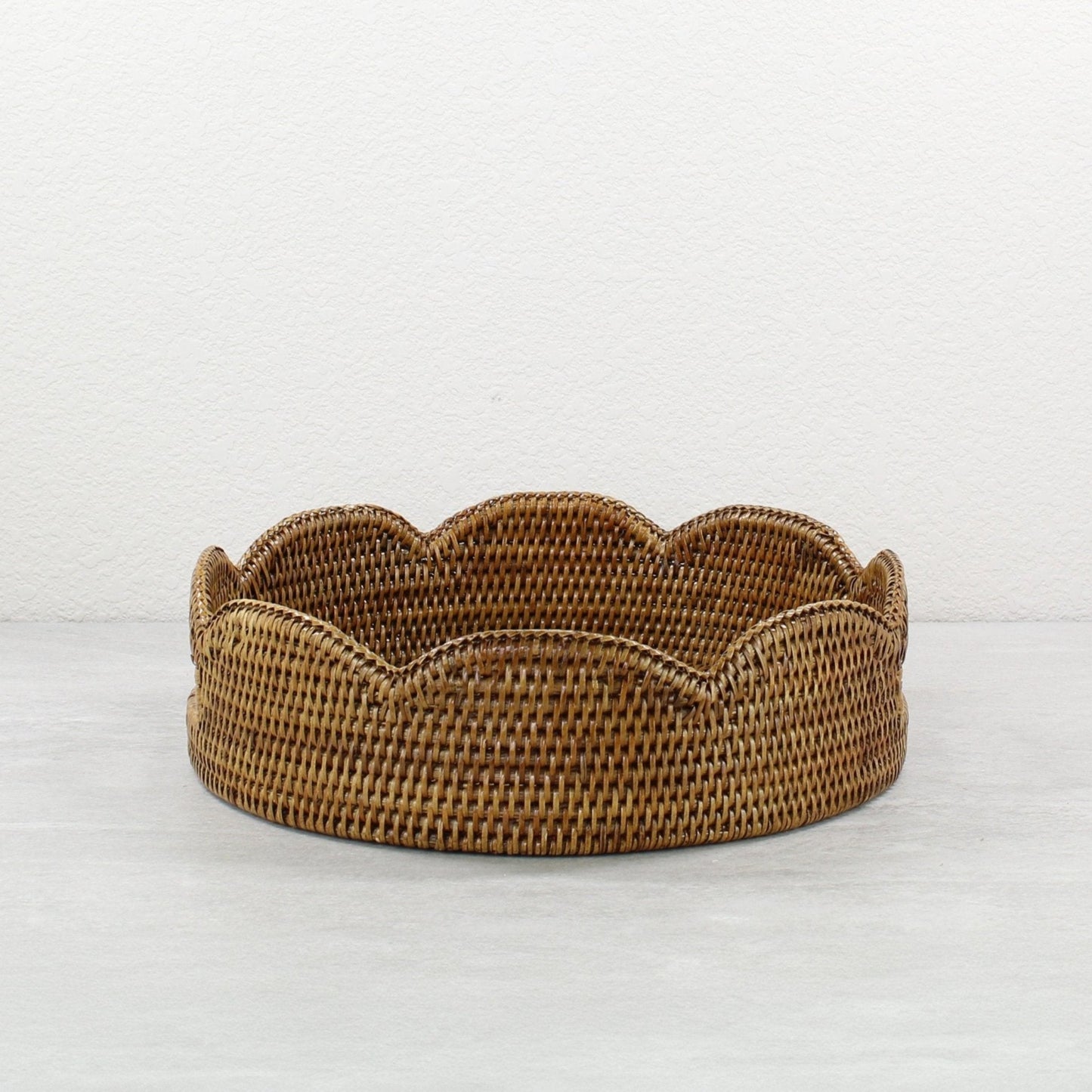 Honey brown scalloped round rattan tray handmade from Burmese rattan, shown empty against a neutral background.