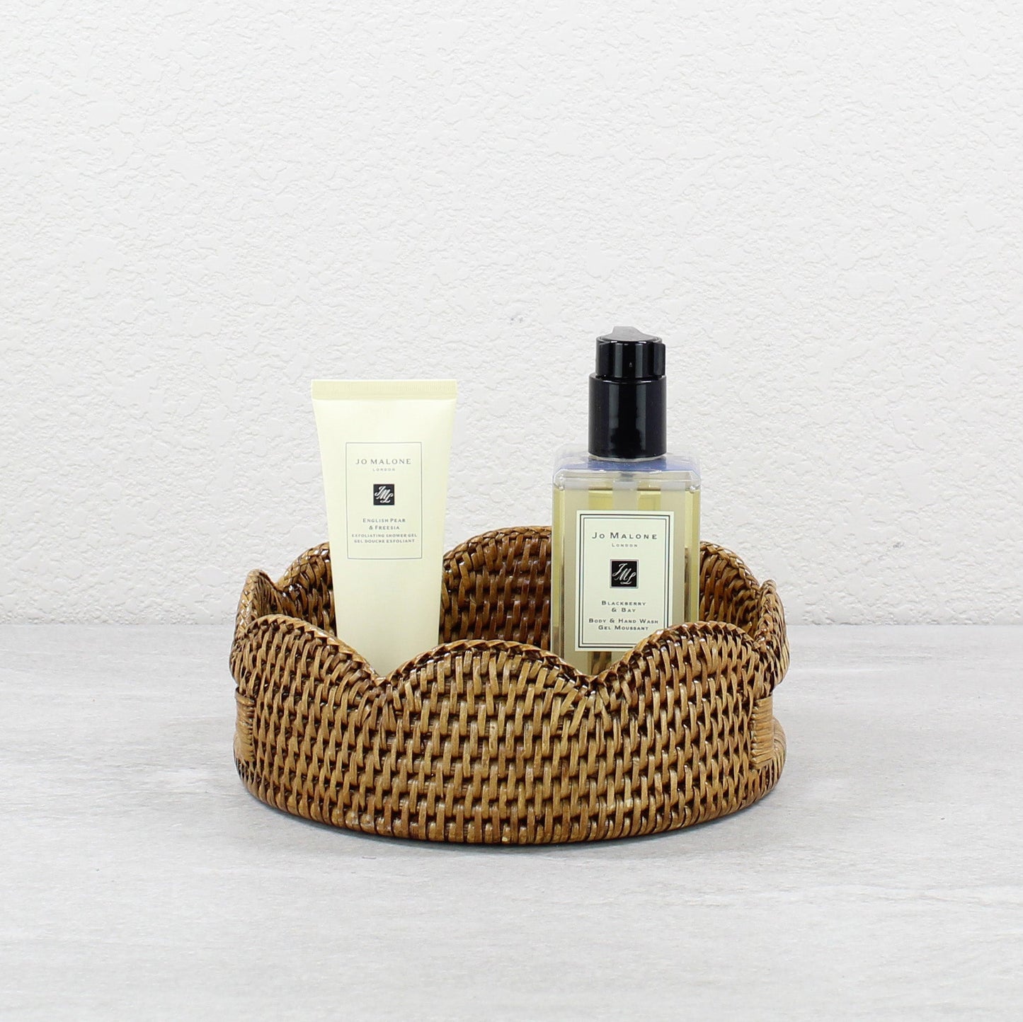 Small scalloped honey brown rattan tray styled with Jo Malone bath products, handwoven eco-friendly bathroom organizer