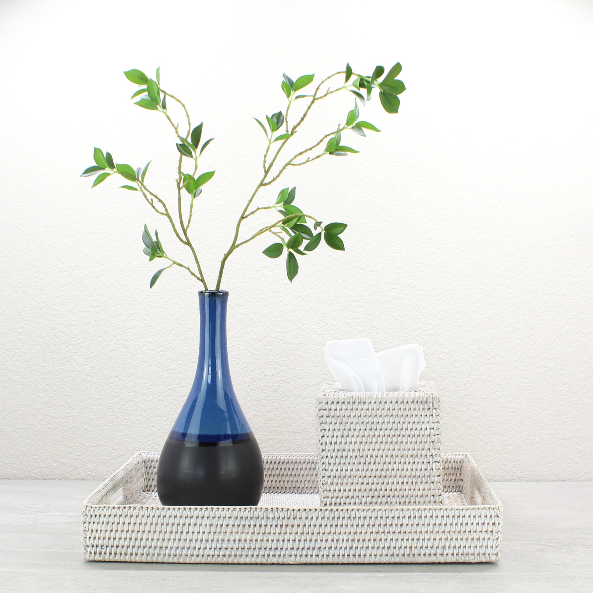 Large whitewash rattan rectangular tray styled with blue vase and tissue box, sustainable home decor organizer for living room or entryway.